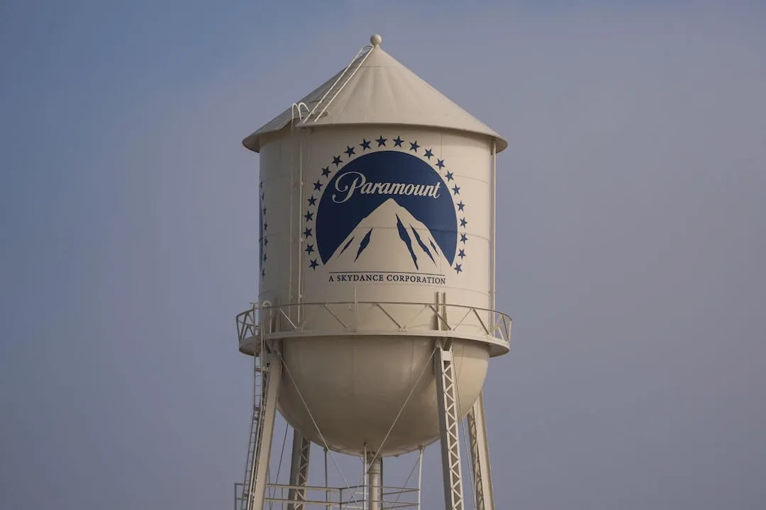 Ejecutivos de Paramount y Warner Bros. Discovery en una mesa de negociación con documentos y logos corporativos